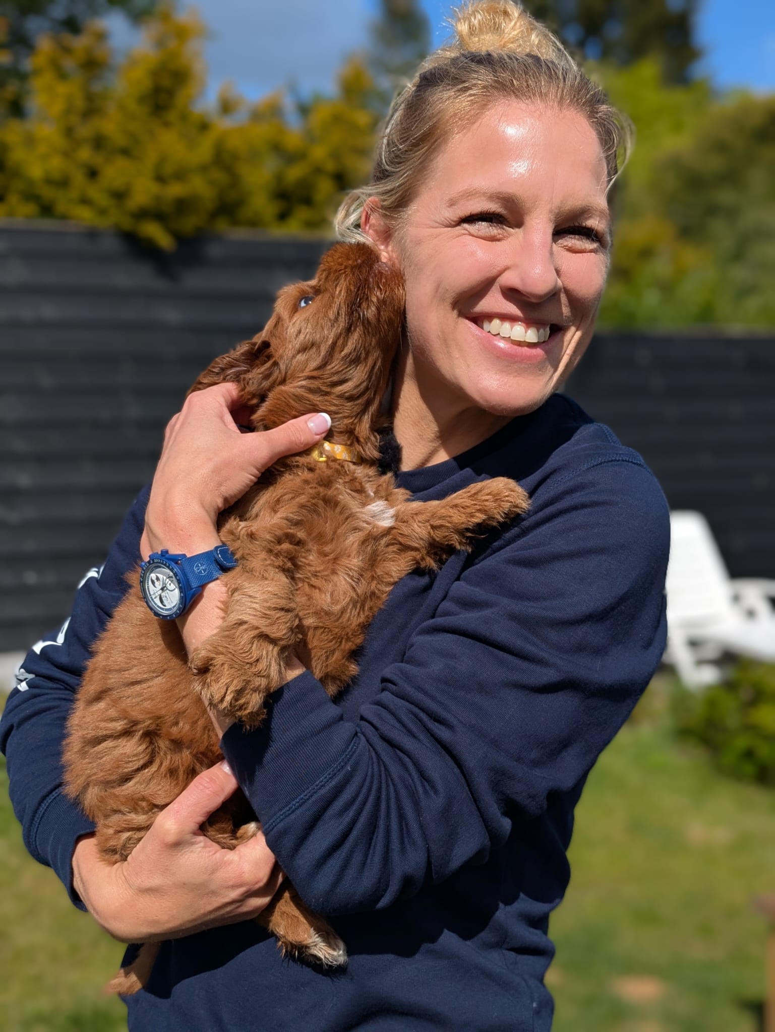 Elien knuffelt een bruine pup in de tuin